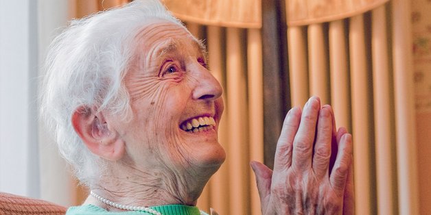 © Cathrin Bach Alte Frau sitzt lachend und klatschend in einem Sessel.